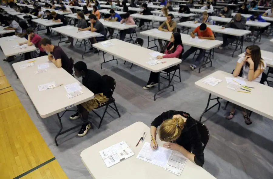 Students taking AP exams at desks in a gymnasium
