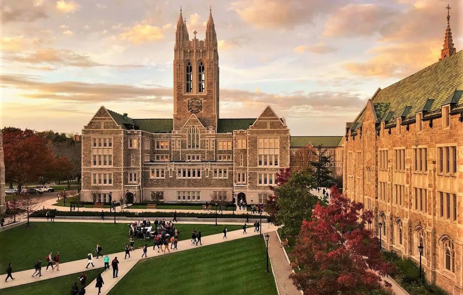 Boston College's Gasson Hall and campus quad at sunset, with students walking the paths